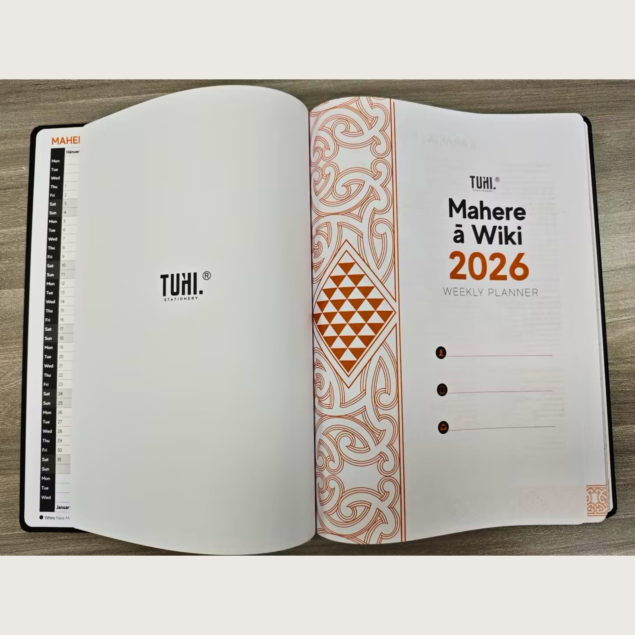 Open weekly planner with TUHI branding on a wooden surface